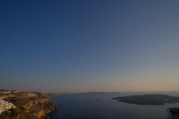 Fototapeta premium Beautiful cliff coastal landscape in Mediterranean Sea Santorini island skyline with blue quiet waters and sky in Greek Islands