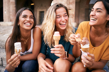 Three young woman eating ice cream cones at the touristic European Roman city on a hot summer day...