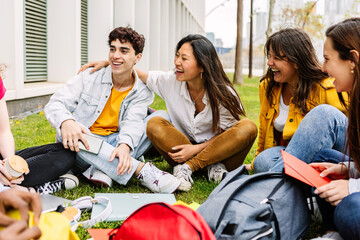 Student college group enjoying time together sitting at college campus park. Millennial school...