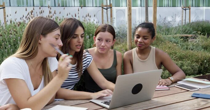 Group of diverse student girls doing a project together with a laptop in a university campus
