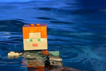 Obraz premium LEGO Minecraft large action figure of main character Alex relaxing in deep blue water of summer swimming pool. 