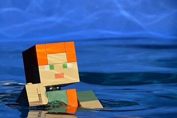 Obraz premium LEGO Minecraft figure of main character Alex is swimming in deep blue water of summer swimming pool. 