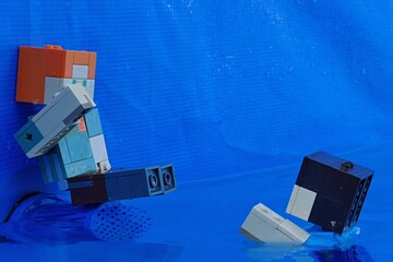 Obraz premium LEGO Minecraft figure of Alex sitting on blue pool filter plastic sifter cover, raising hand to Steve swimming towards her