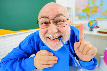 Back to school. Funny teacher with notebook pointing finger up. Happy tutor in glasses with...