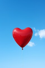 Fototapeta na wymiar Red heart-shaped balloon on blue sky background. Valentines day