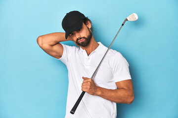 Long-haired golfer with club and hat touching back of head, thinking and making a choice.