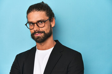 Close-up of bearded businessman in suit against a blue studio background.