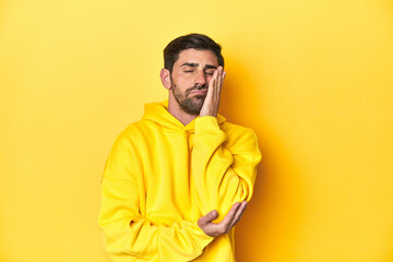Man in yellow hoodie, monochrome studio backdrop who is bored, fatigued and need a relax day.