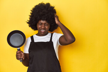 Home-cooking African-American woman holding a pan being shocked, she has remembered important...