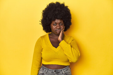 Fototapeta na wymiar African-American woman with afro, studio yellow background having a strong teeth pain, molar ache.