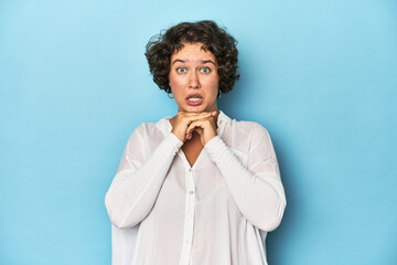 Young Caucasian woman with short hair praying for luck, amazed and opening mouth looking to front.