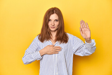 Business-dressed redhead, formal studio shot taking an oath, putting hand on chest.