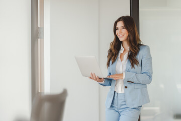 Positive confident smiling businesswoman professional manager using laptop, working online looking...