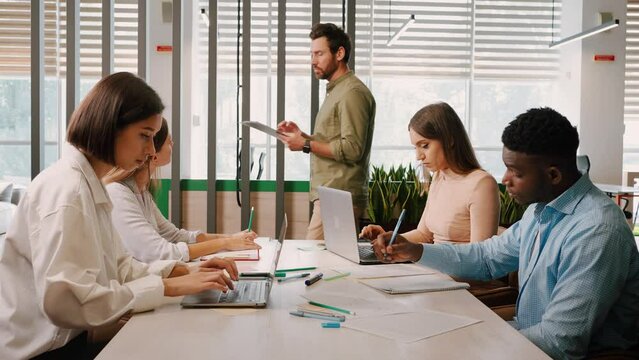 Manager gives tasks to employees at company business meeting