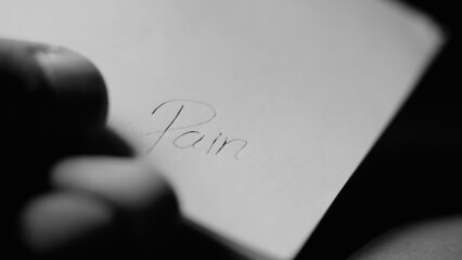 Escribiendo en papel blanco la palabra dolor  foto en blanco y negro