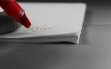 Escribiendo en papel blanco con boligrafo rojo la palabra 