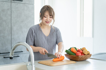 キッチンで料理・野菜を切るアジア人女性・妊婦・プレママ
