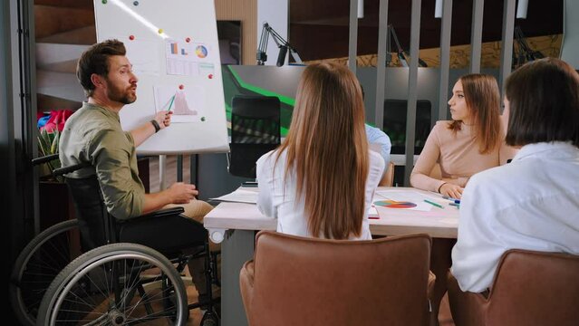 Young man in wheelchair summarizes teamwork at meeting