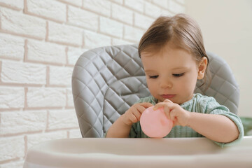 Fototapeta premium Cute little baby with toy in high chair indoors. Space for text