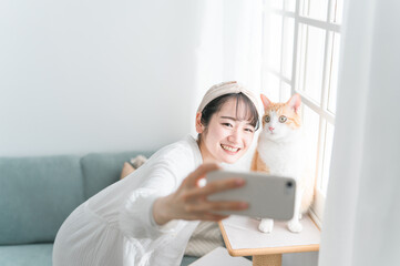 愛猫と一緒にスマホで写真を撮るアジア人女性
