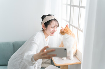 愛猫と一緒にスマホで写真を撮るアジア人女性
