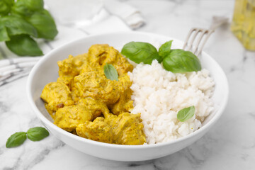 Delicious rice and chicken with curry sauce on white marble table, closeup