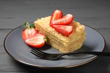 Piece of delicious Napoleon cake with strawberries on grey wooden table, closeup