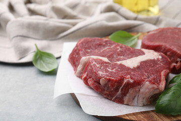 Fresh raw cut beef and basil leaves on grey table, closeup. Space for text