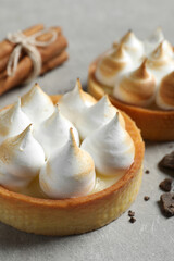 Tartlets with meringue on light grey table, closeup. Tasty dessert