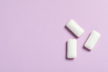 Tasty white chewing gums on lilac background, flat lay. Space for text