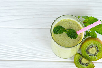 Kiwi yogurt fruit juice smoothie and green kiwi juice drink healthy, delicious taste in a glass for weight loss on a white wooden background.