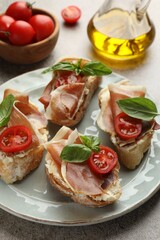 Tasty sandwiches with cured ham, basil and tomatoes on table, closeup
