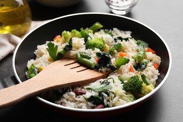 Tasty fried rice with vegetables served on black table, closeup