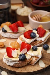 Tasty sandwiches with brie cheese, fresh berries and almond flakes on table