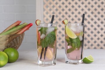 Tasty rhubarb cocktail with lime on white wooden table indoors