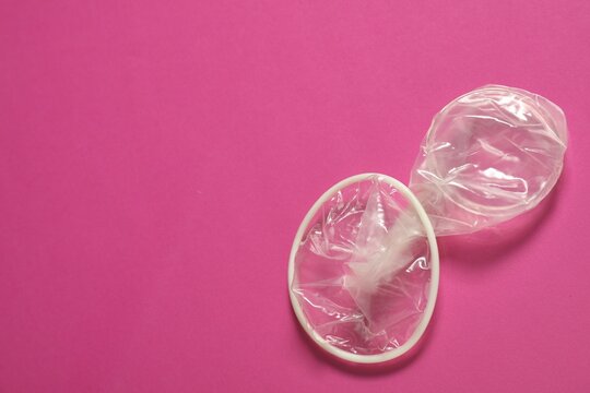 Unrolled female condom on pink background, space for text. Safe sex