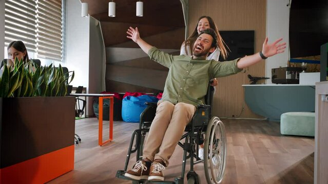 Woman runs pushing wheelchair with laughing male colleague