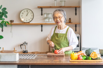 家のキッチンで料理を作るアジア人の高齢者女性
