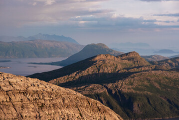 Sunset over Norwegian archipelago mountains. Dusk at Smaltinden, Luröy, Helgeland, Nordnorge. Arctic twilight over sharp norway mountain ranges at the atlantic coastline. Summer night fjelltur Norge