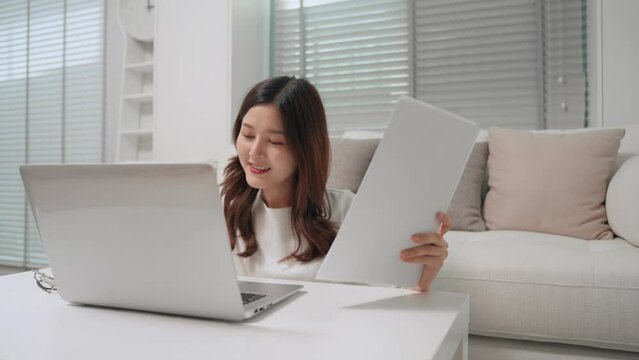 Asian business woman working and checking detail of document by laptop computer at home. Freelancer asian woman making to order from customer at home office store.