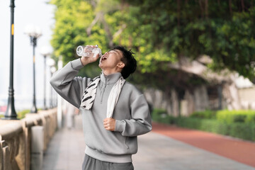 Asian man is drinking water after doing sports. 