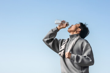 Asian man is drinking water after doing sports. 