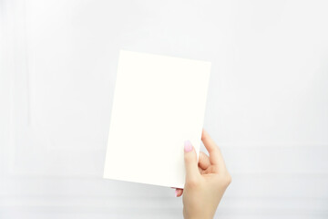 Hand holding blank white 5x7 invitation card for wedding invitation, greeting card, birthday invite, baby shower invite