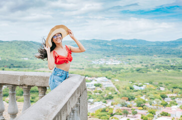 Happy vacationer woman in hat on a viewpoint. Portrait of beautiful tourist girl in a viewpoint,...