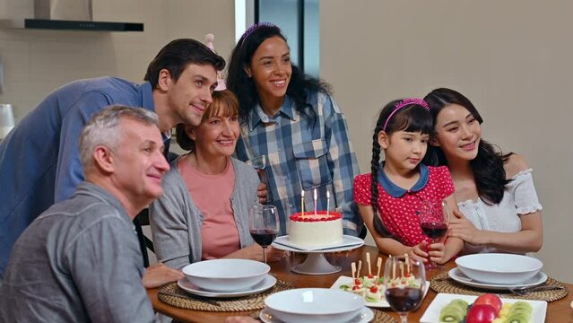 Happy big multi-ethnic family celebrating grandmother's birthday in cozy dining room at home. Big Family take photo and video  together in kitchen room on night at home.