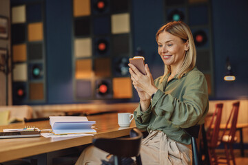 Woman entrepreneur use phone in modern coworking during working day. Distance work concept