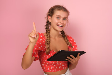 Young optimistic positive Caucasian woman copywriter with tablet computer in hands shows finger up...