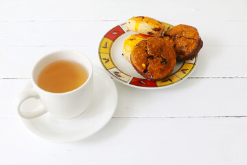 A cup of hot tea served with scone cookies on white background