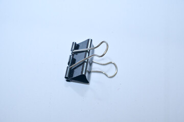 A binder clip, less commonly known as a paperclip or folding clip or bobby clip or buckle, is a simple tool for holding sheets of paper together on a white background