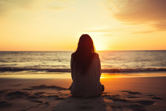 Unhappy lonely depressed woman, she is sitting on the beach at sunset, depression concept